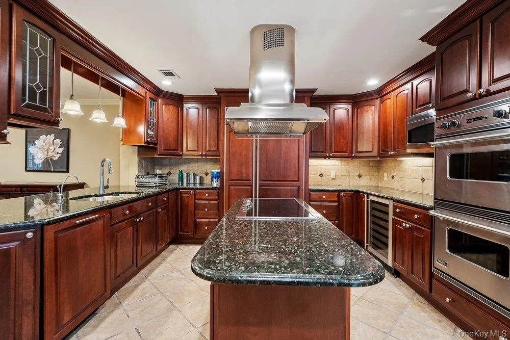 Kitchen featuring extensive wood cabinetry, granite countertops, and stainless steel appliances Kitchen featuring extensive wood cabinetry, granite countertops, and stainless steel appliances