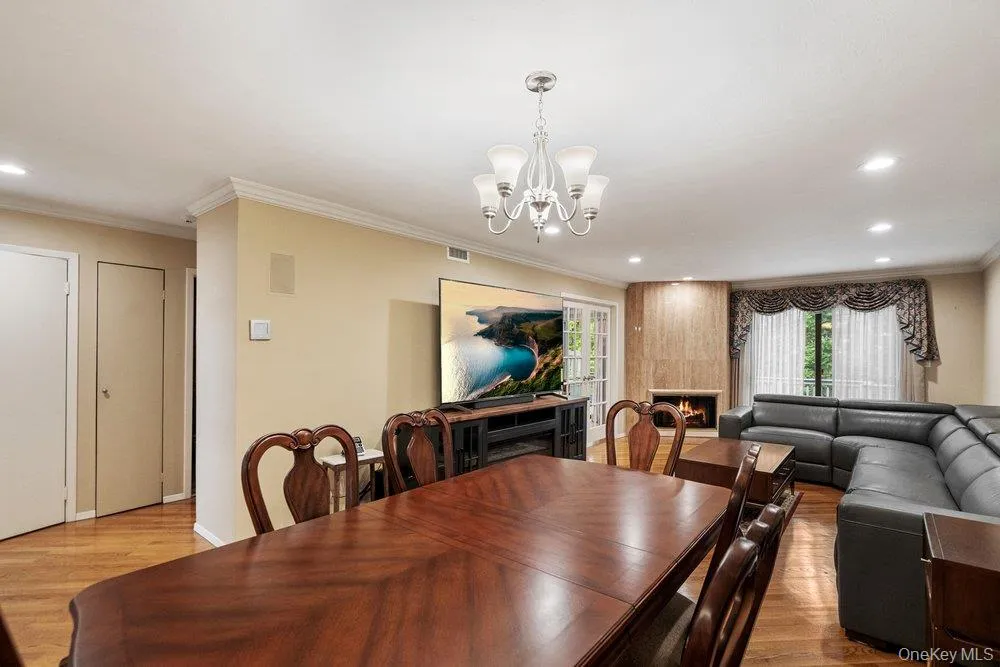 Expansive living area with wood-finish flooring, recessed lighting, and crown molding Expansive living area with wood-finish flooring, recessed lighting, and crown molding