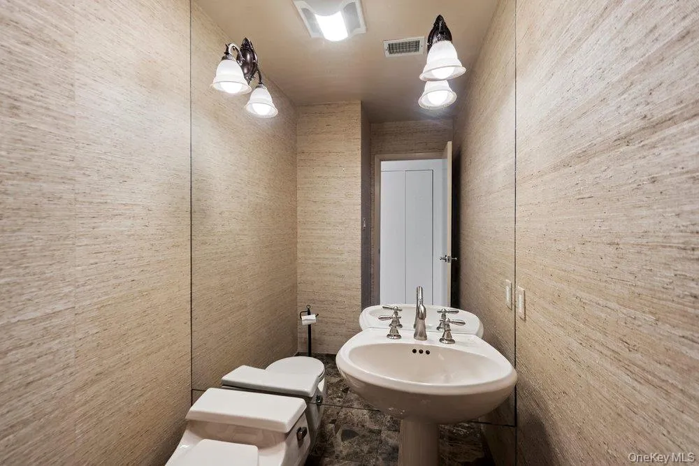 Pedestal sink with chrome fixtures and overhead vanity lighting Pedestal sink with chrome fixtures and overhead vanity lighting