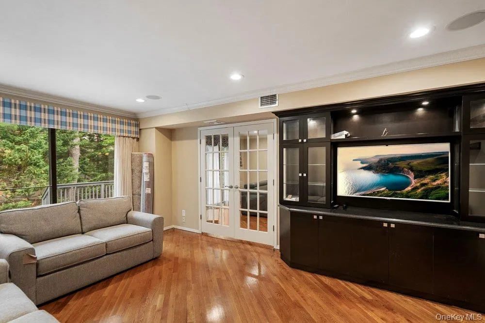 Wood-finish flooring throughout, featuring a large built-in media cabinet with display shelving and accent lighting Wood-finish flooring throughout, featuring a large built-in media cabinet with display shelving and accent lighting