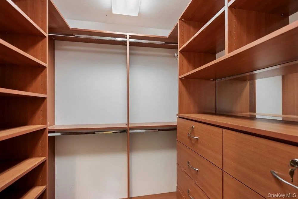 Custom closet system with wood-finish shelving and built-in drawers Custom closet system with wood-finish shelving and built-in drawers