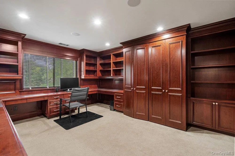 Built-in wood-finish cabinetry and shelving throughout, featuring a U-shaped desk with integrated drawers Built-in wood-finish cabinetry and shelving throughout, featuring a U-shaped desk with integrated drawers