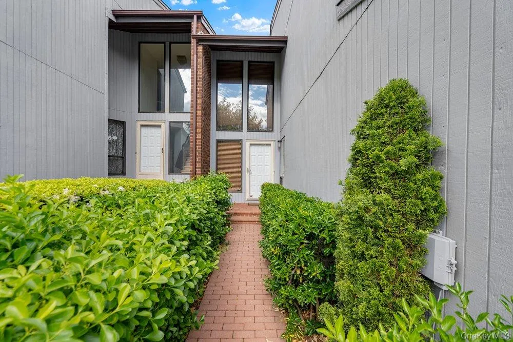Brick walkway bordered by manicured hedges leading to two distinct entryways Brick walkway bordered by manicured hedges leading to two distinct entryways