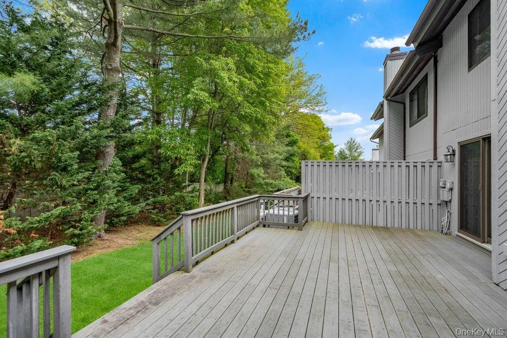 Spacious outdoor deck featuring wood decking, a privacy screen, and direct access to a grassy yard Spacious outdoor deck featuring wood decking, a privacy screen, and direct access to a grassy yard