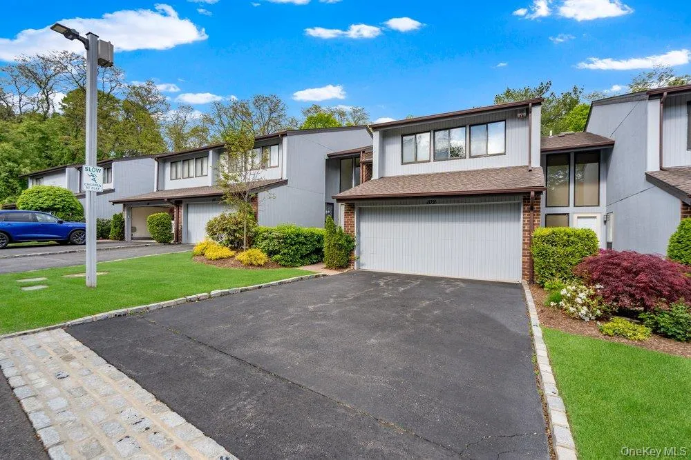 Contemporary townhome exterior featuring light gray siding, a brown shingle roof, and a two-car garage with a light gray door Contemporary townhome exterior featuring light gray siding, a brown shingle roof, and a two-car garage with a light gray door