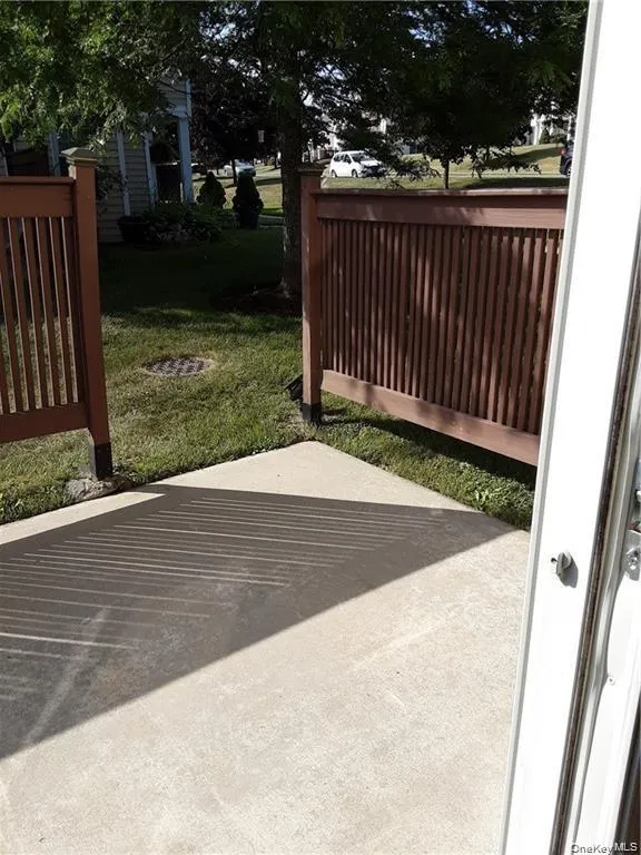 Outdoor concrete patio with brown slatted fencing, bordered by a manicured lawn Outdoor concrete patio with brown slatted fencing, bordered by a manicured lawn