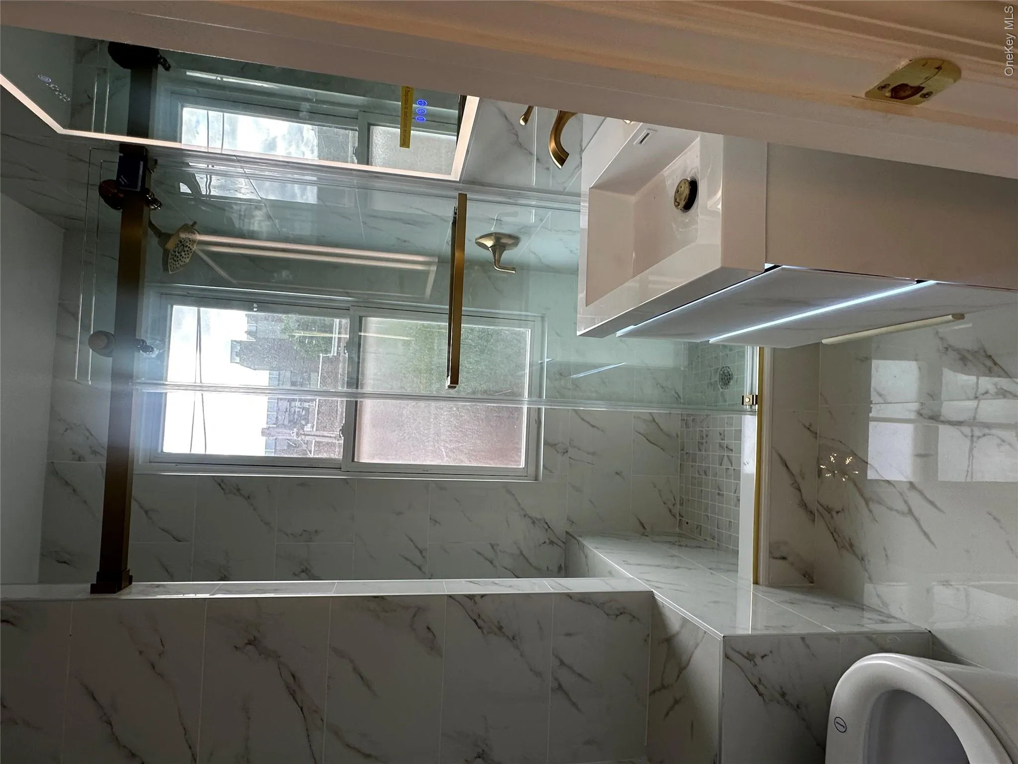 Contemporary bathroom featuring a walk-in shower with clear glass enclosure and gold-finish hardware Contemporary bathroom featuring a walk-in shower with clear glass enclosure and gold-finish hardware
