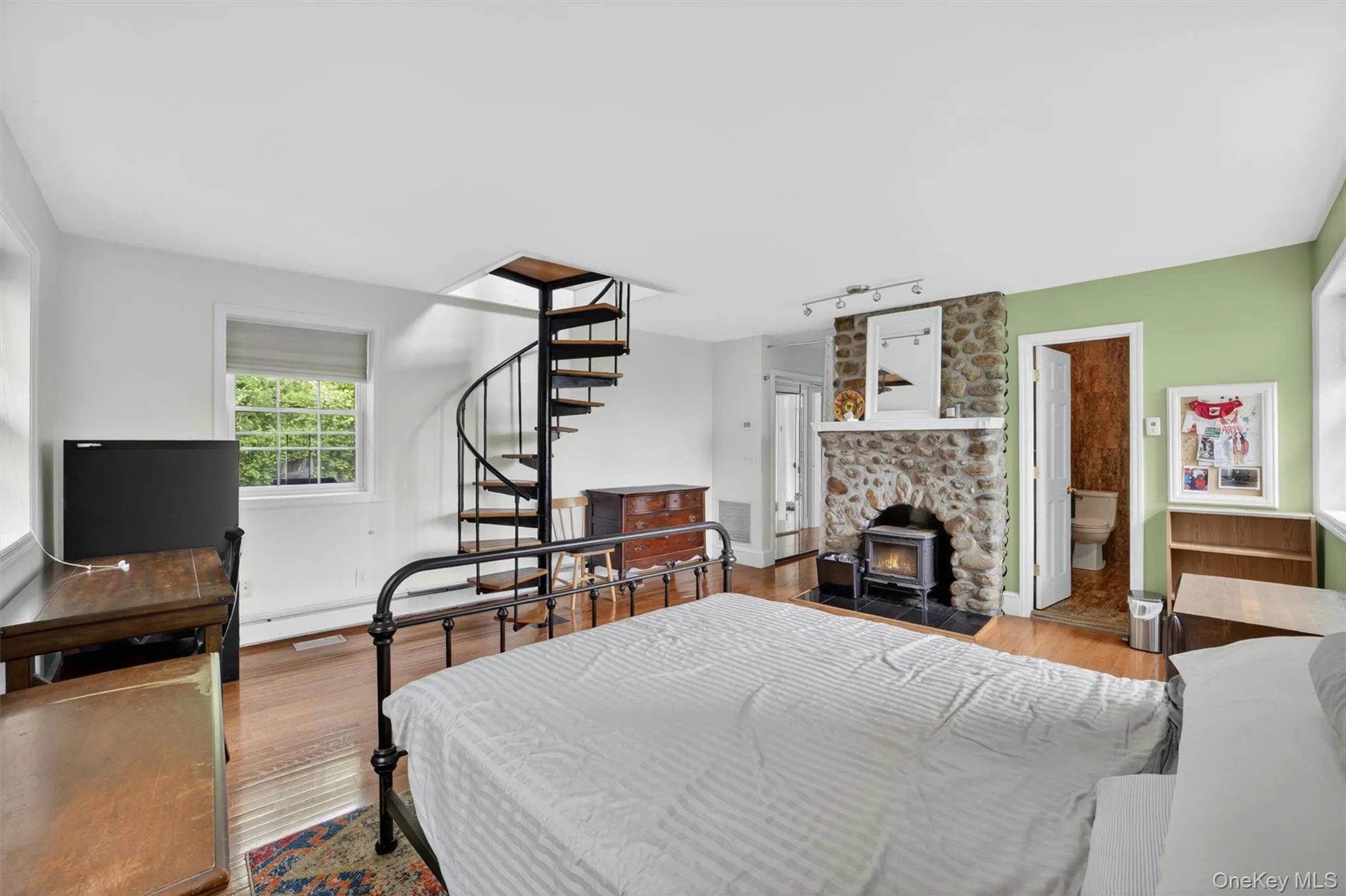Main floor primary bedroom featuring beautiful Hudson River views, a striking stone fireplace, and a warm, inviting atmosphere. Main floor primary bedroom featuring beautiful Hudson River views, a striking stone fireplace, and a warm, inviting atmosphere.