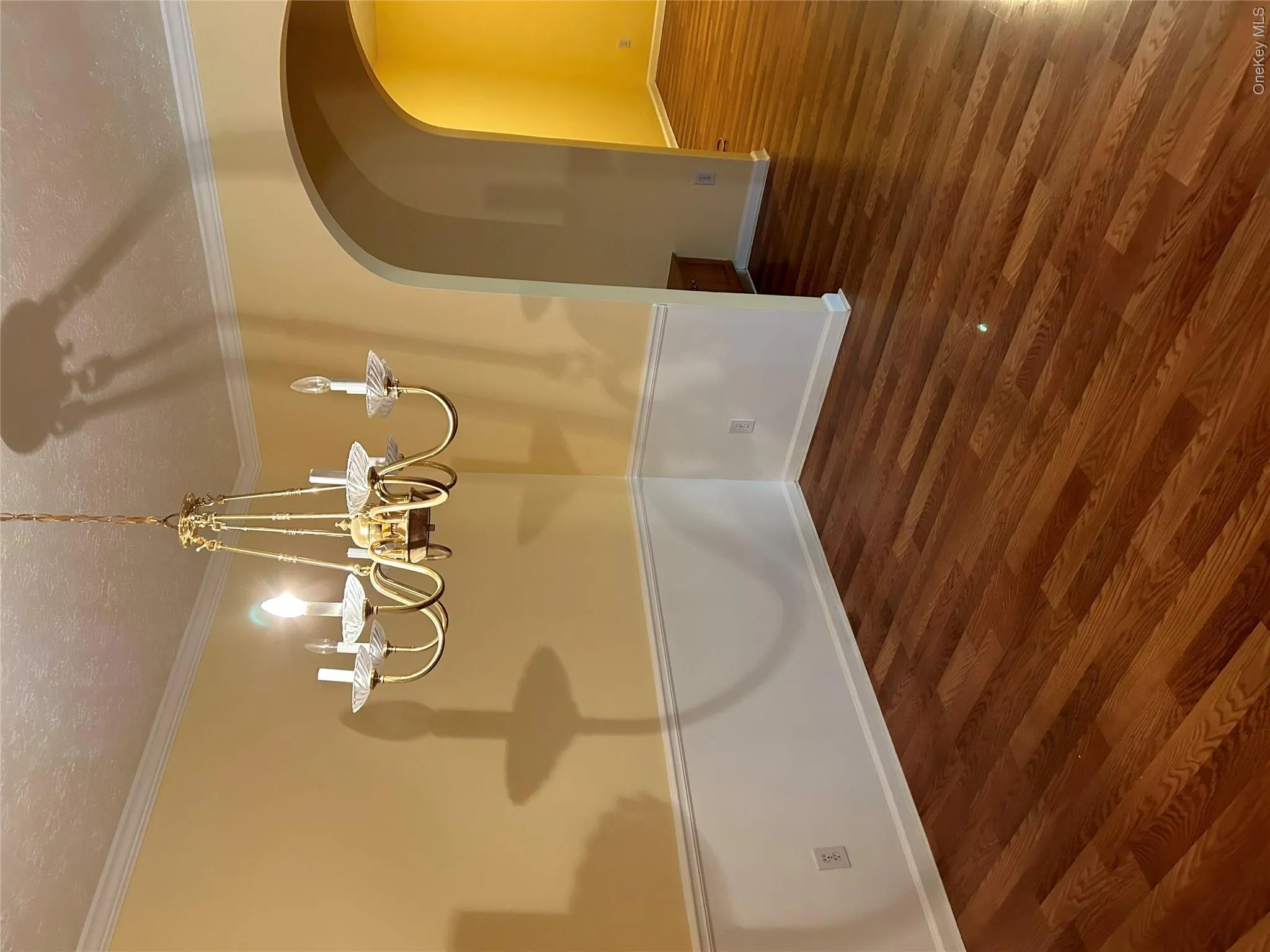 Dining area featuring wood-finish flooring, two-tone wall treatment, crown molding, and an arched doorway Dining area featuring wood-finish flooring, two-tone wall treatment, crown molding, and an arched doorway