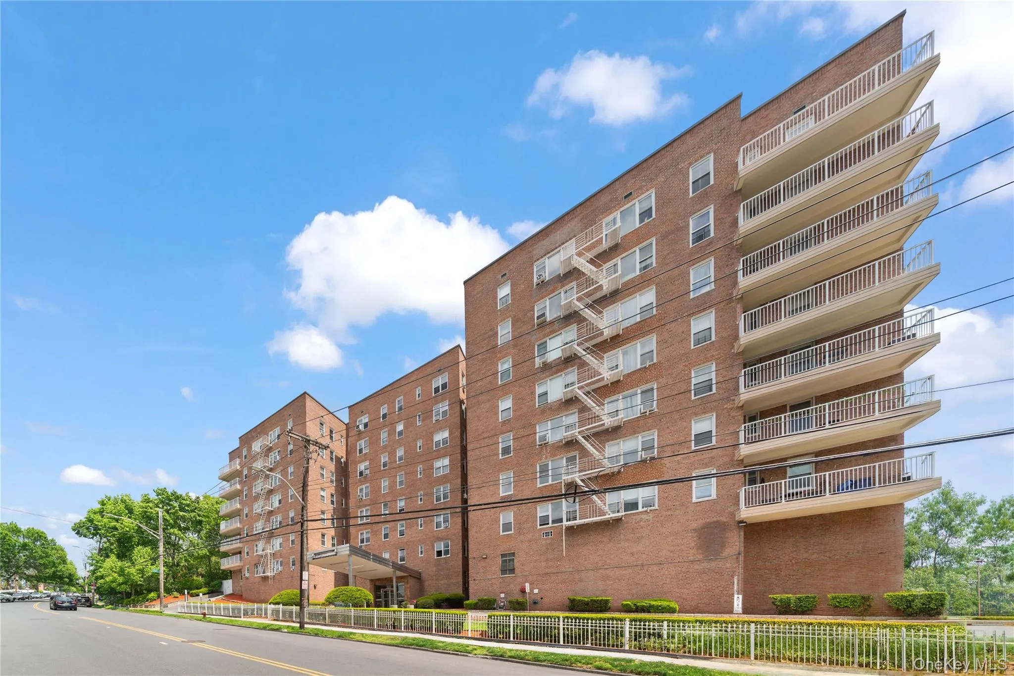 Multi-story brick facade building featuring an angled balcony design, multiple windows, and a street-level entrance Multi-story brick facade building featuring an angled balcony design, multiple windows, and a street-level entrance