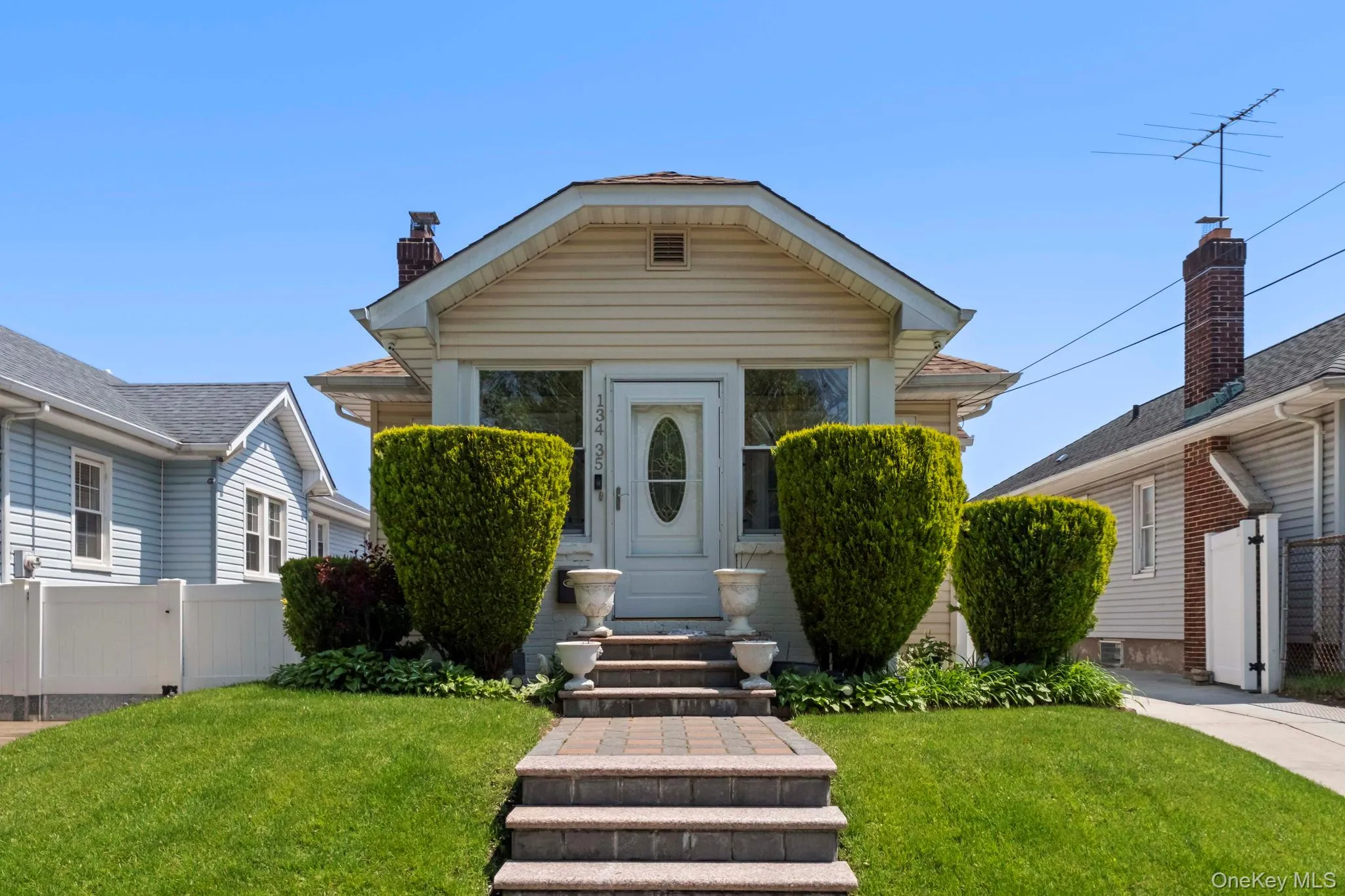 Front exterior featuring light-colored siding, a gabled roofline, and a prominent chimney Front exterior featuring light-colored siding, a gabled roofline, and a prominent chimney