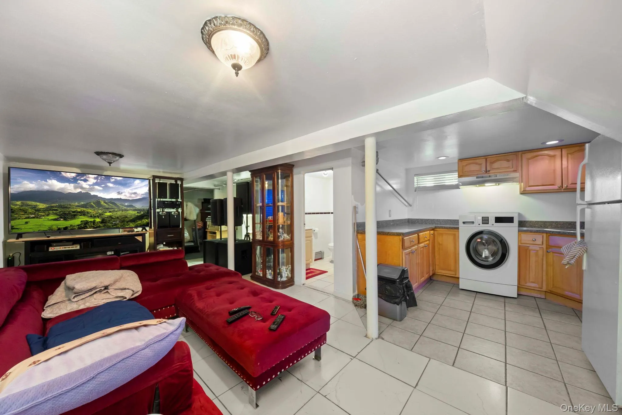 Downstairs living space with tile flooring throughout, featuring a sink, refrigerator and washer Downstairs living space with tile flooring throughout, featuring a sink, refrigerator and washer