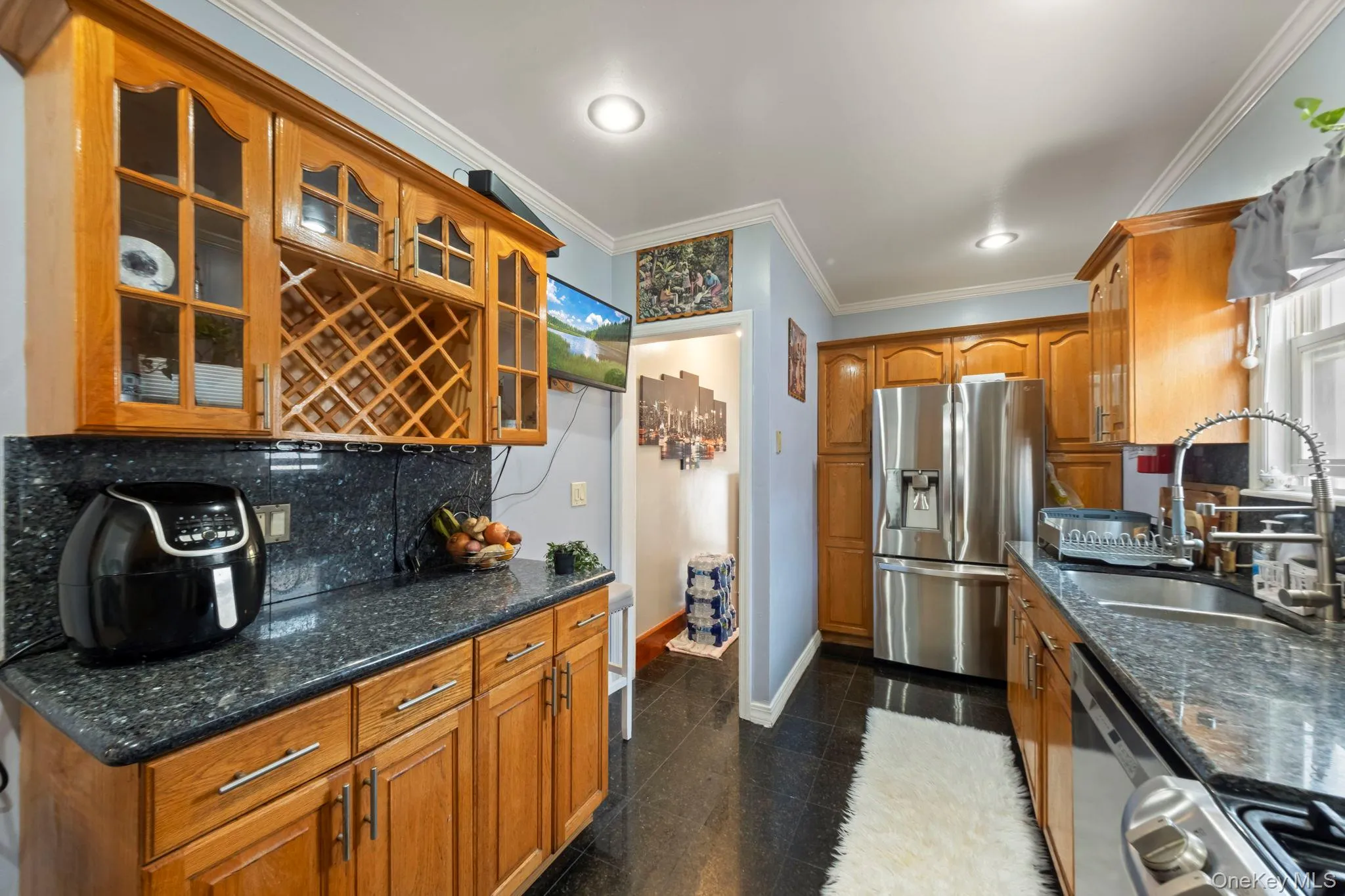 Kitchen featuring wood cabinetry, dark countertops, and stainless steel appliances Kitchen featuring wood cabinetry, dark countertops, and stainless steel appliances