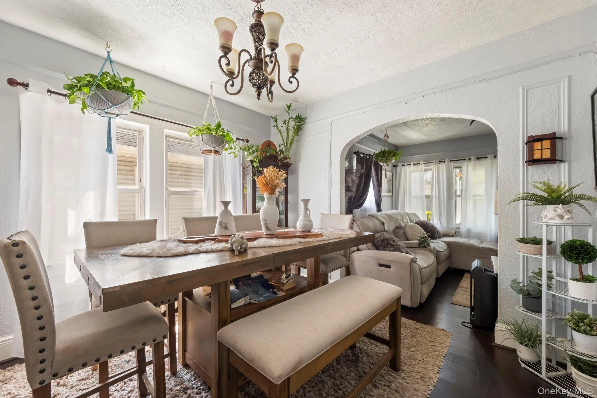 Dining area featuring a rustic wood-finish table, upholstered seating, dark wood-finish flooring, and a decorative archway Dining area featuring a rustic wood-finish table, upholstered seating, dark wood-finish flooring, and a decorative archway