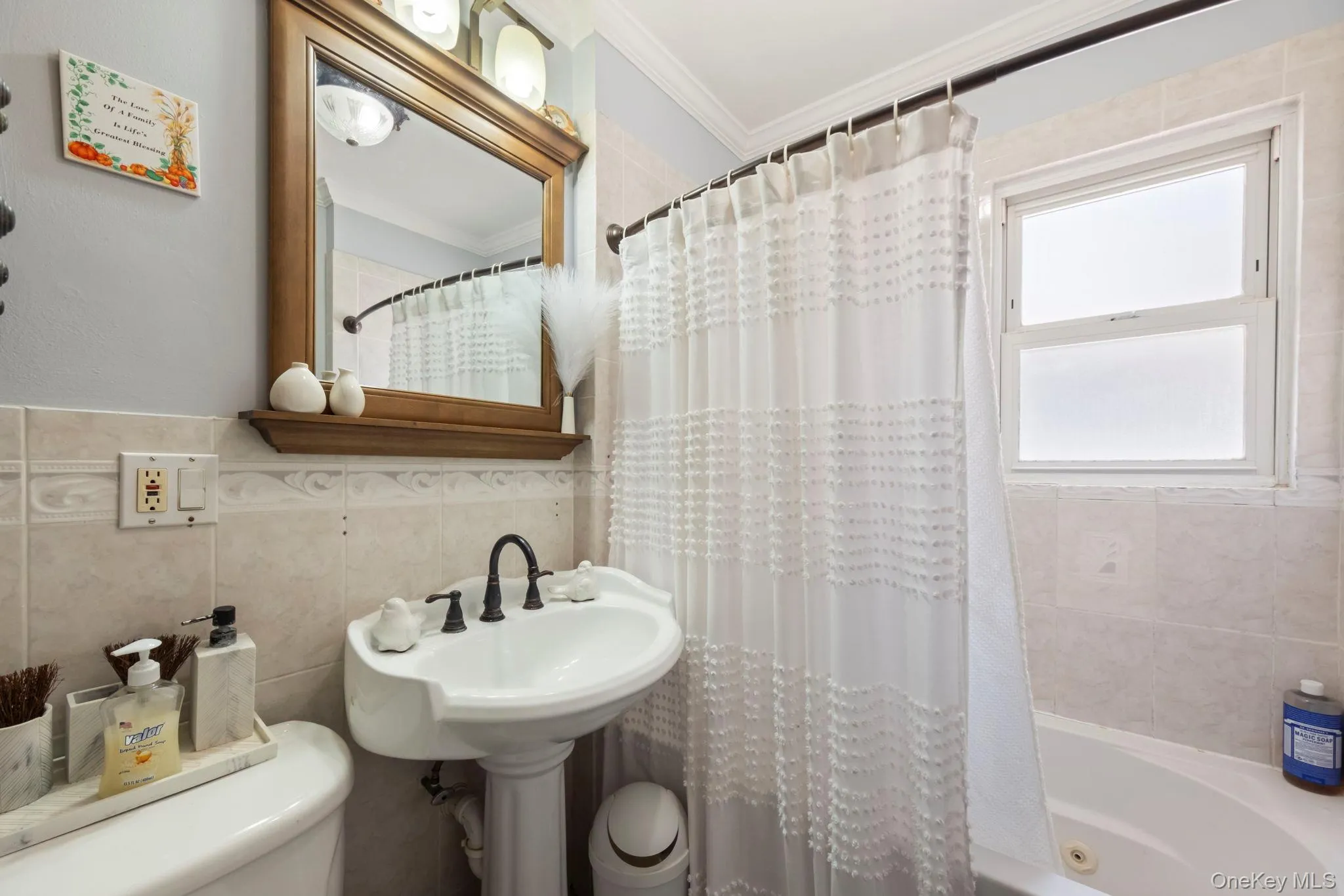 Pedestal sink with black-finish faucet and a wooden framed mirror with overhead lighting Pedestal sink with black-finish faucet and a wooden framed mirror with overhead lighting