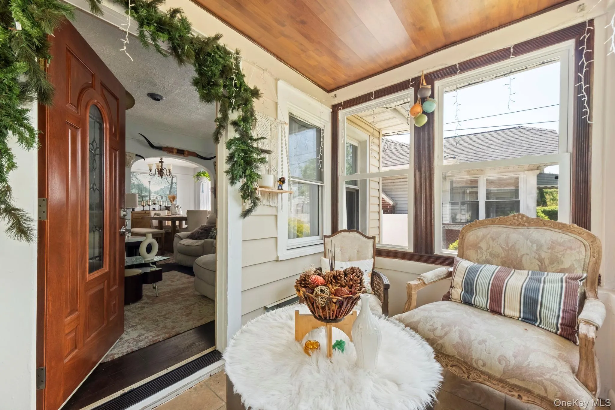 Enclosed porch featuring a wood-paneled ceiling, multiple windows with dark wood trim, and light beige siding Enclosed porch featuring a wood-paneled ceiling, multiple windows with dark wood trim, and light beige siding