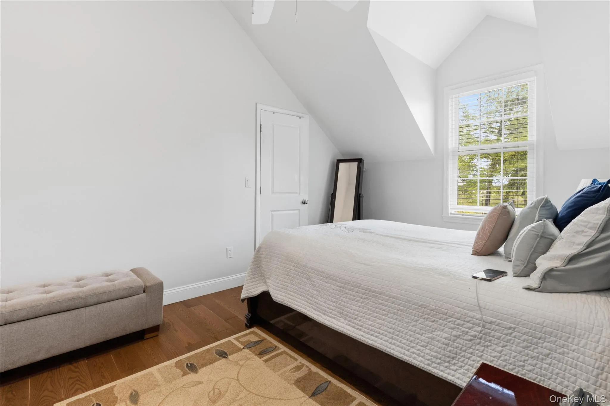 Room #1 with a sloped ceiling, wood-finish flooring, white walls, and a large window with blinds Room #1 with a sloped ceiling, wood-finish flooring, white walls, and a large window with blinds
