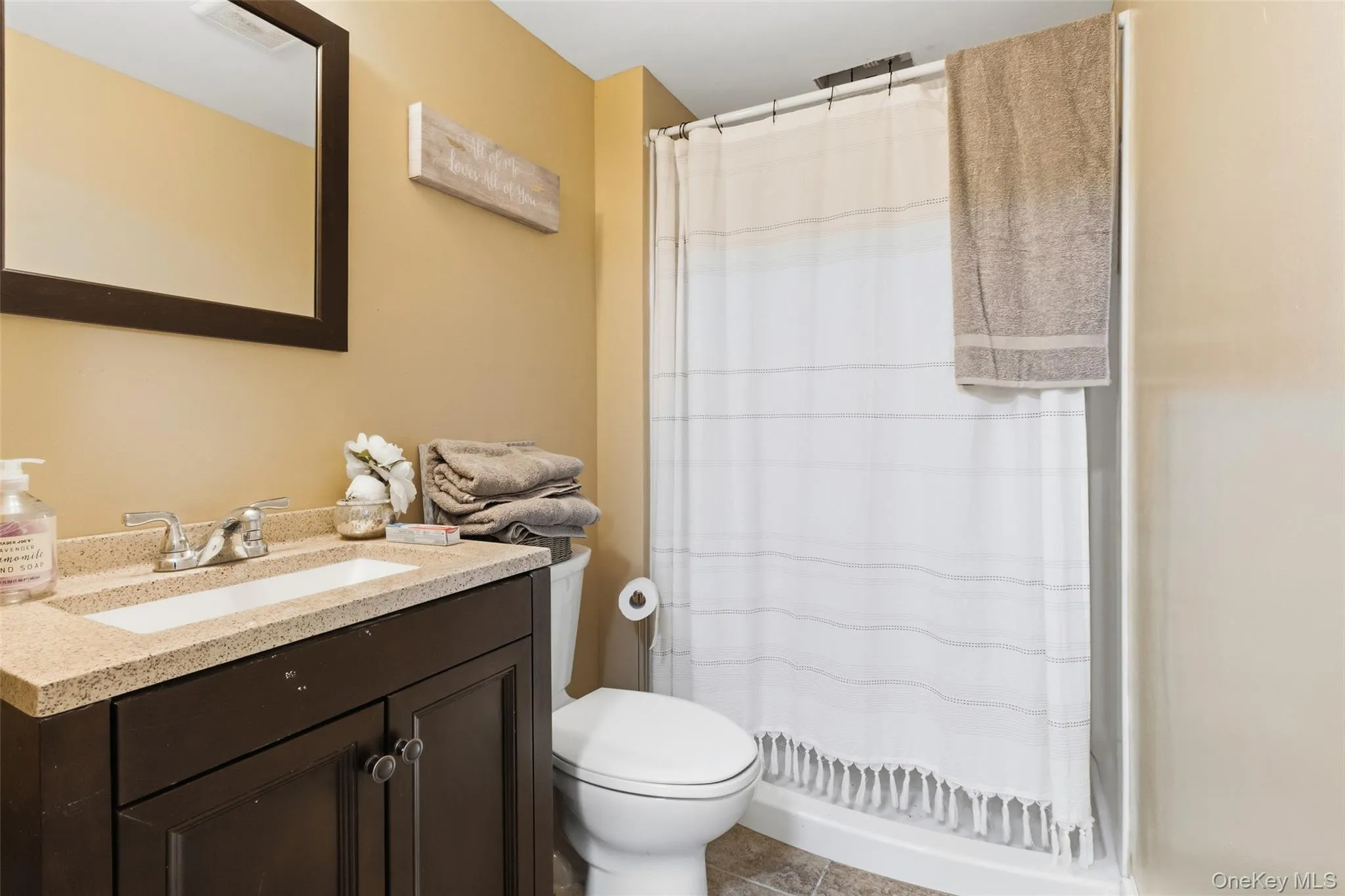 Basement Bathroom featuring a vanity with a light-colored countertop, dark wood-finish cabinetry, and a chrome faucet Basement Bathroom featuring a vanity with a light-colored countertop, dark wood-finish cabinetry, and a chrome faucet