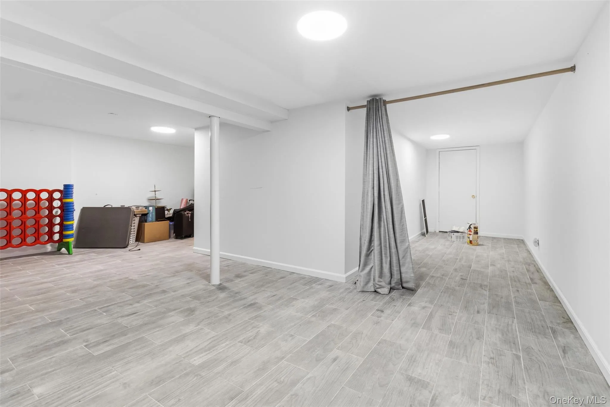 Spacious lower level featuring light gray wood-finish flooring, recessed circular lighting, and painted support columns Spacious lower level featuring light gray wood-finish flooring, recessed circular lighting, and painted support columns