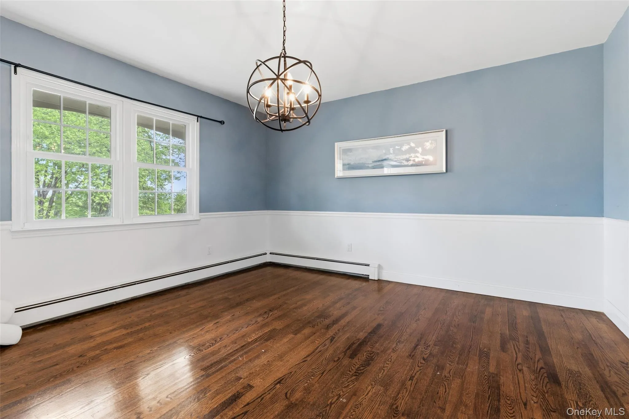 Hardwood flooring, two-tone wall treatment with wainscoting, and a decorative orb chandelier Hardwood flooring, two-tone wall treatment with wainscoting, and a decorative orb chandelier