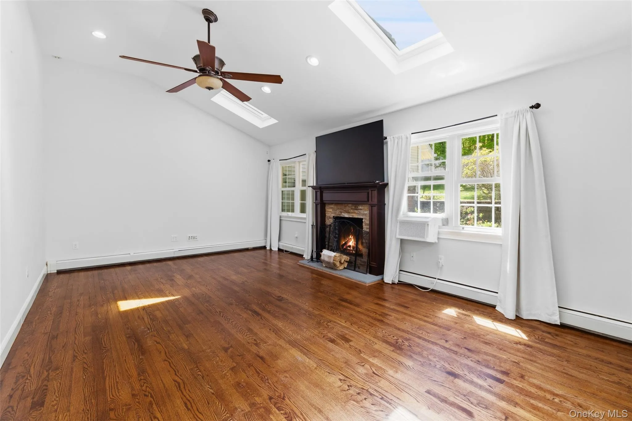 Spacious room featuring vaulted ceilings, fire place, recessed lighting, and rich wood-finish flooring Spacious room featuring vaulted ceilings, fire place, recessed lighting, and rich wood-finish flooring