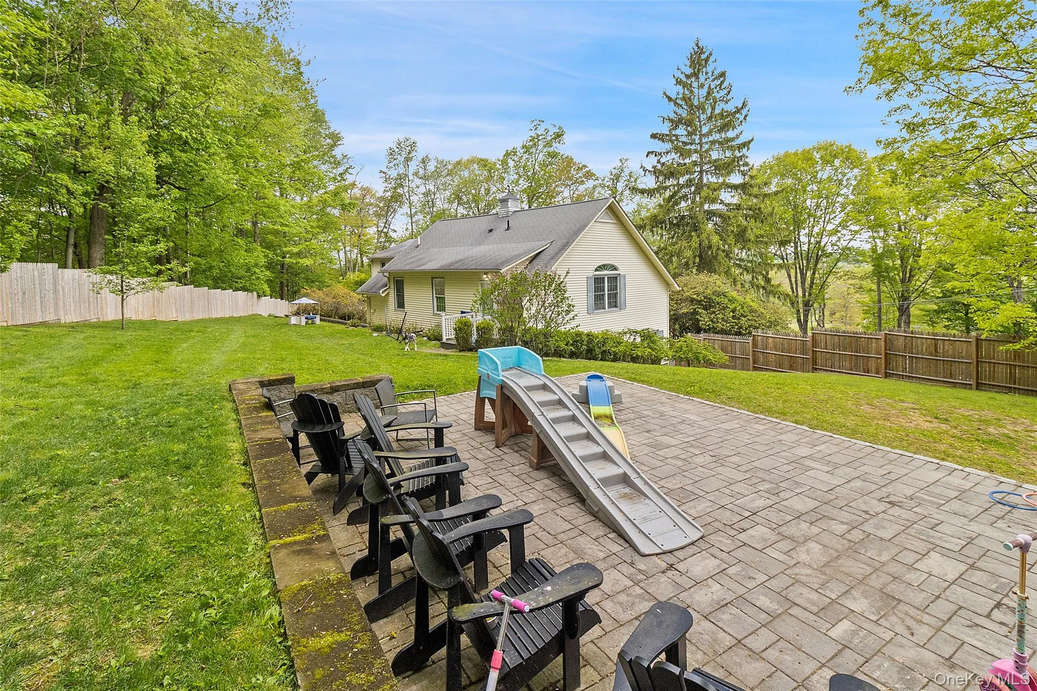 Expansive paver patio bordered by a low retaining wall and a large grassy yard Expansive paver patio bordered by a low retaining wall and a large grassy yard