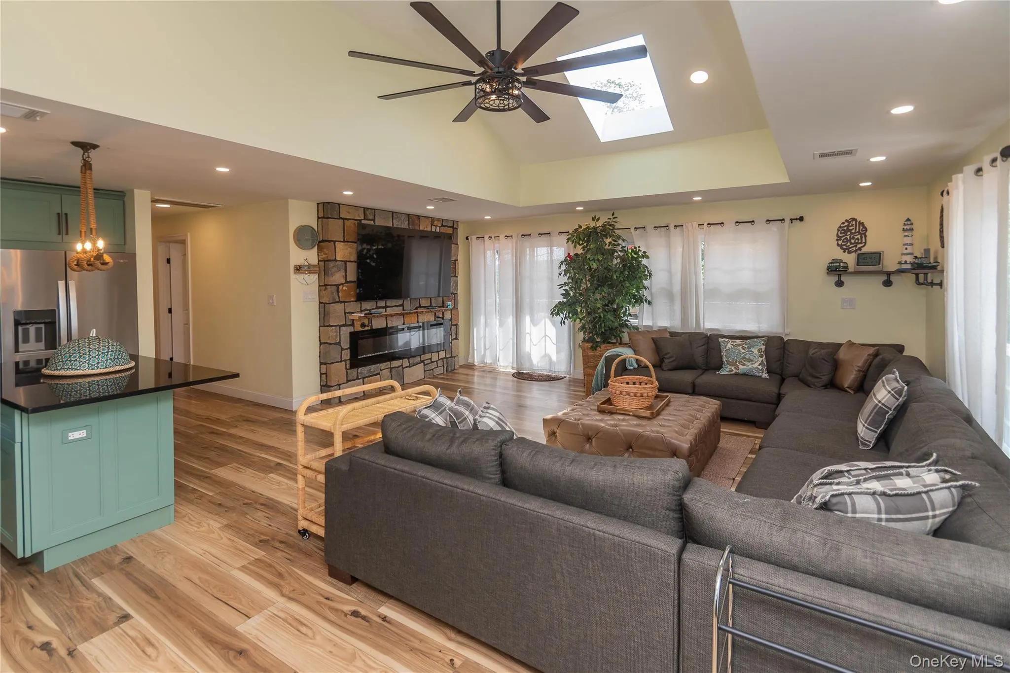 Living room featuring ceiling fan, light wood finished floors, recessed lighting, a skylight, and vaulted ceiling Living room featuring ceiling fan, light wood finished floors, recessed lighting, a skylight, and vaulted ceiling