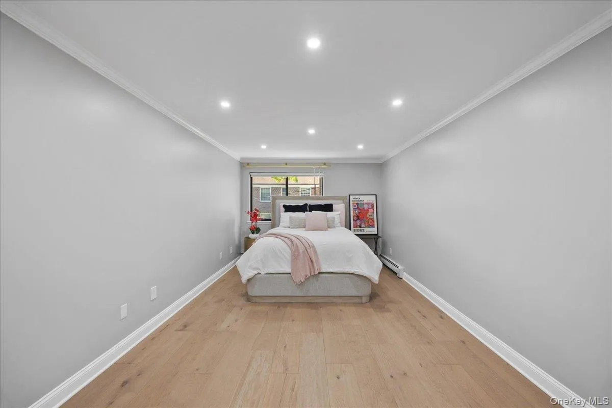 Spacious room featuring light wood-finish flooring, recessed lighting, crown molding, and a window providing natural light Spacious room featuring light wood-finish flooring, recessed lighting, crown molding, and a window providing natural light