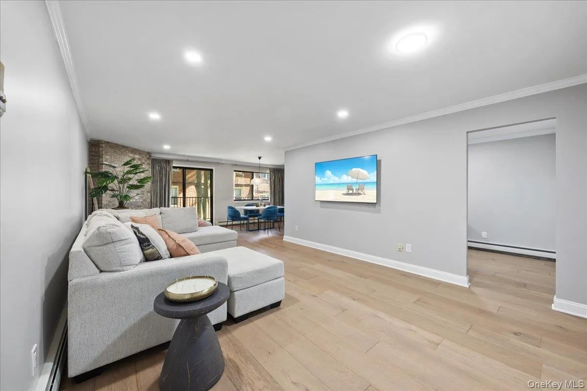 Open-concept living area featuring wood-finish flooring, recessed lighting, and crown molding Open-concept living area featuring wood-finish flooring, recessed lighting, and crown molding