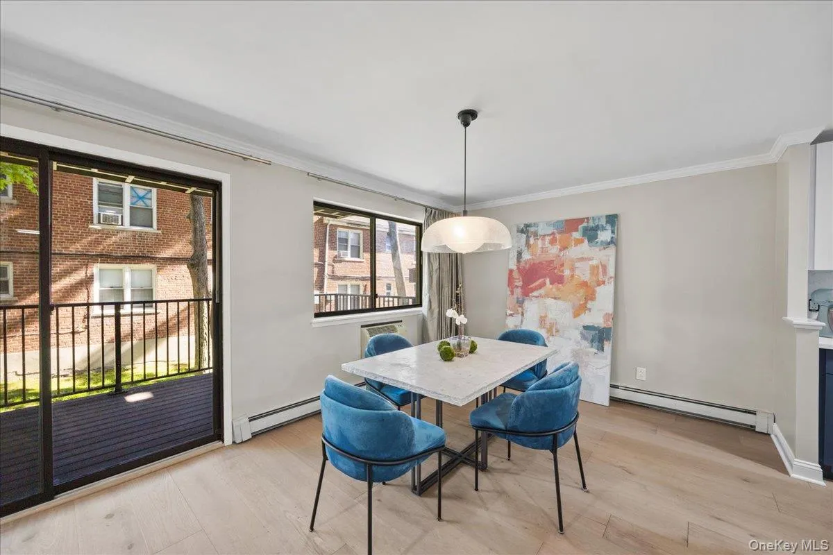 Dining area featuring light wood-finish flooring, a contemporary pendant light fixture, and a large sliding glass door with a balcony Dining area featuring light wood-finish flooring, a contemporary pendant light fixture, and a large sliding glass door with a balcony