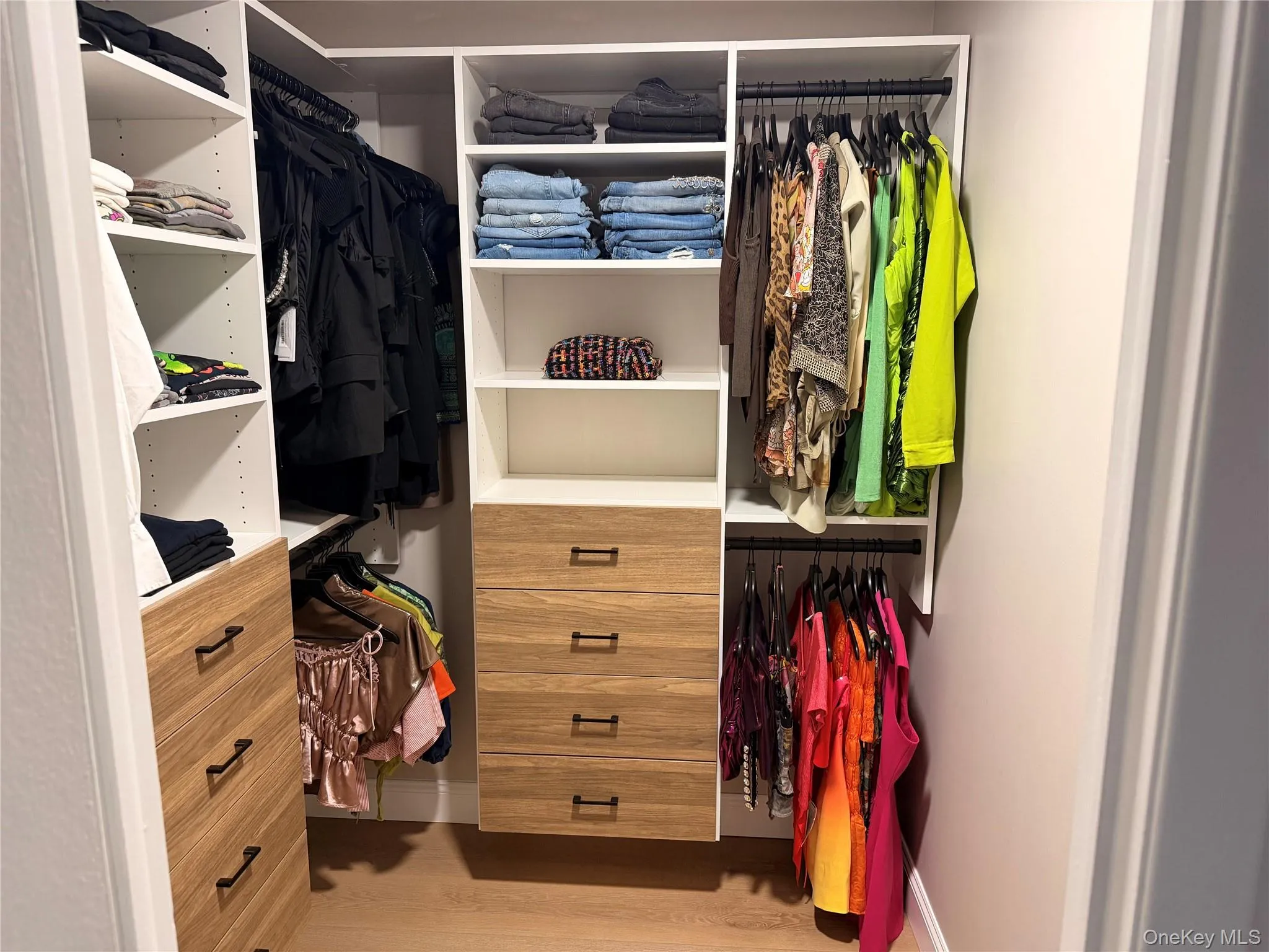 Custom closet system featuring white shelving and wood-finish drawer fronts Custom closet system featuring white shelving and wood-finish drawer fronts