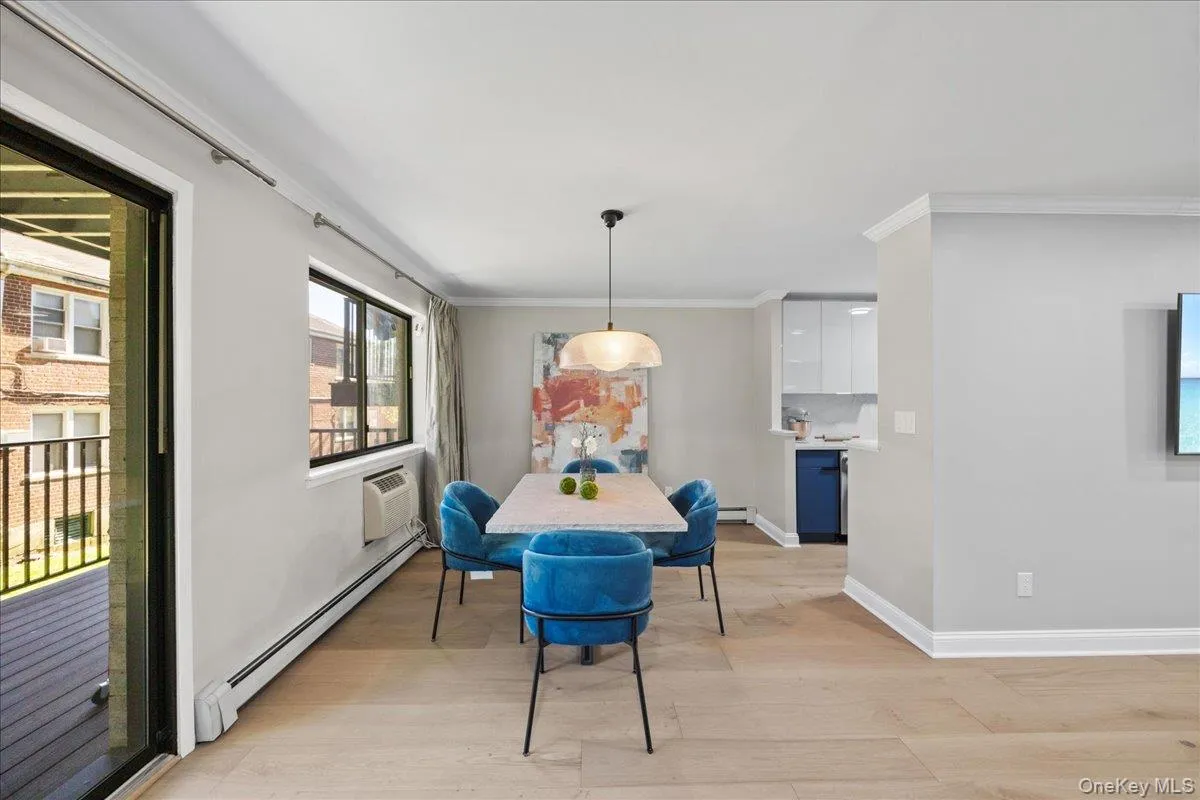 Open-concept dining area featuring light wood-finish flooring, a contemporary pendant light fixture, and crown molding Open-concept dining area featuring light wood-finish flooring, a contemporary pendant light fixture, and crown molding