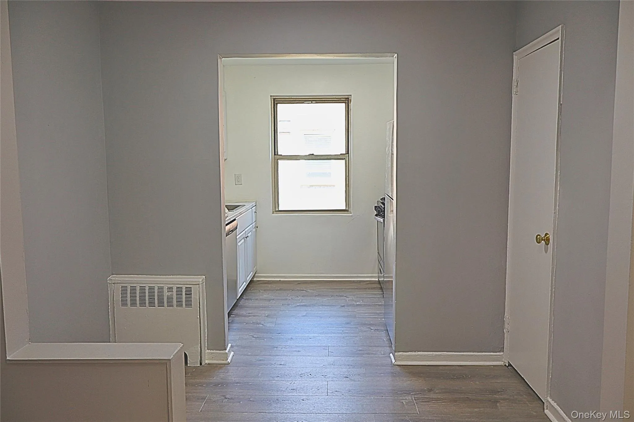 Kitchen entry featuring wood-finish flooring, light gray wall paint, and white baseboards Kitchen entry featuring wood-finish flooring, light gray wall paint, and white baseboards