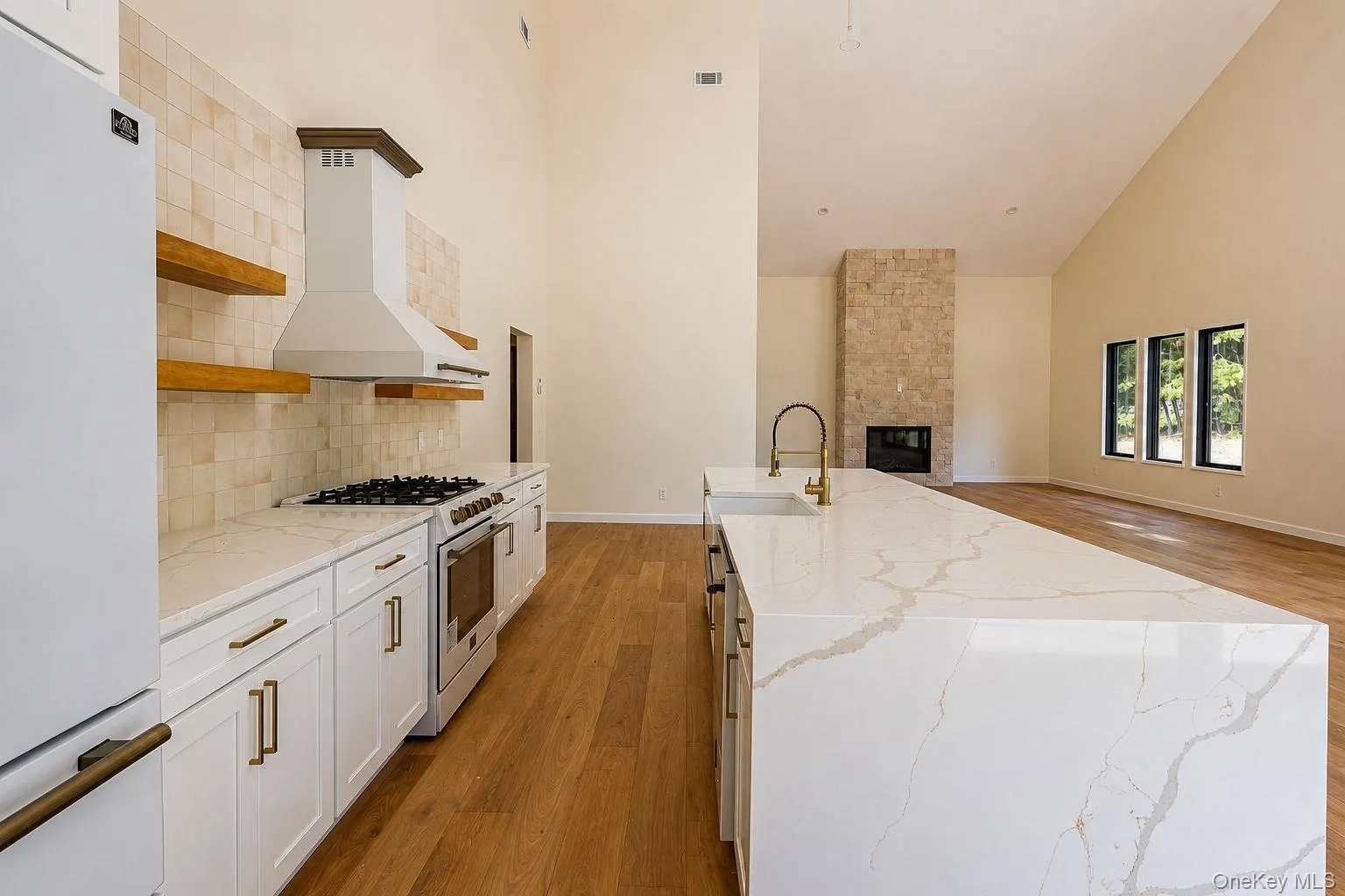 Open-concept kitchen featuring luxury Forno appliances, an expansive island with an integrated sink and brass faucet Open-concept kitchen featuring luxury Forno appliances, an expansive island with an integrated sink and brass faucet