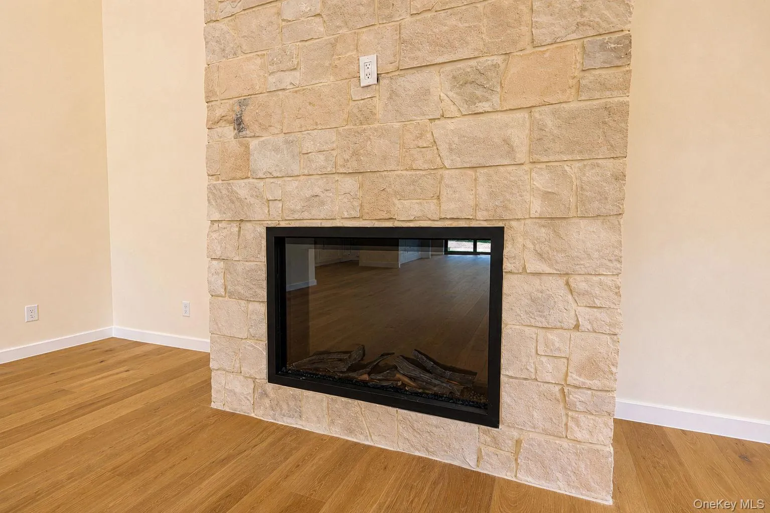Stone-clad fireplace featuring a black-framed glass-fronted insert Stone-clad fireplace featuring a black-framed glass-fronted insert