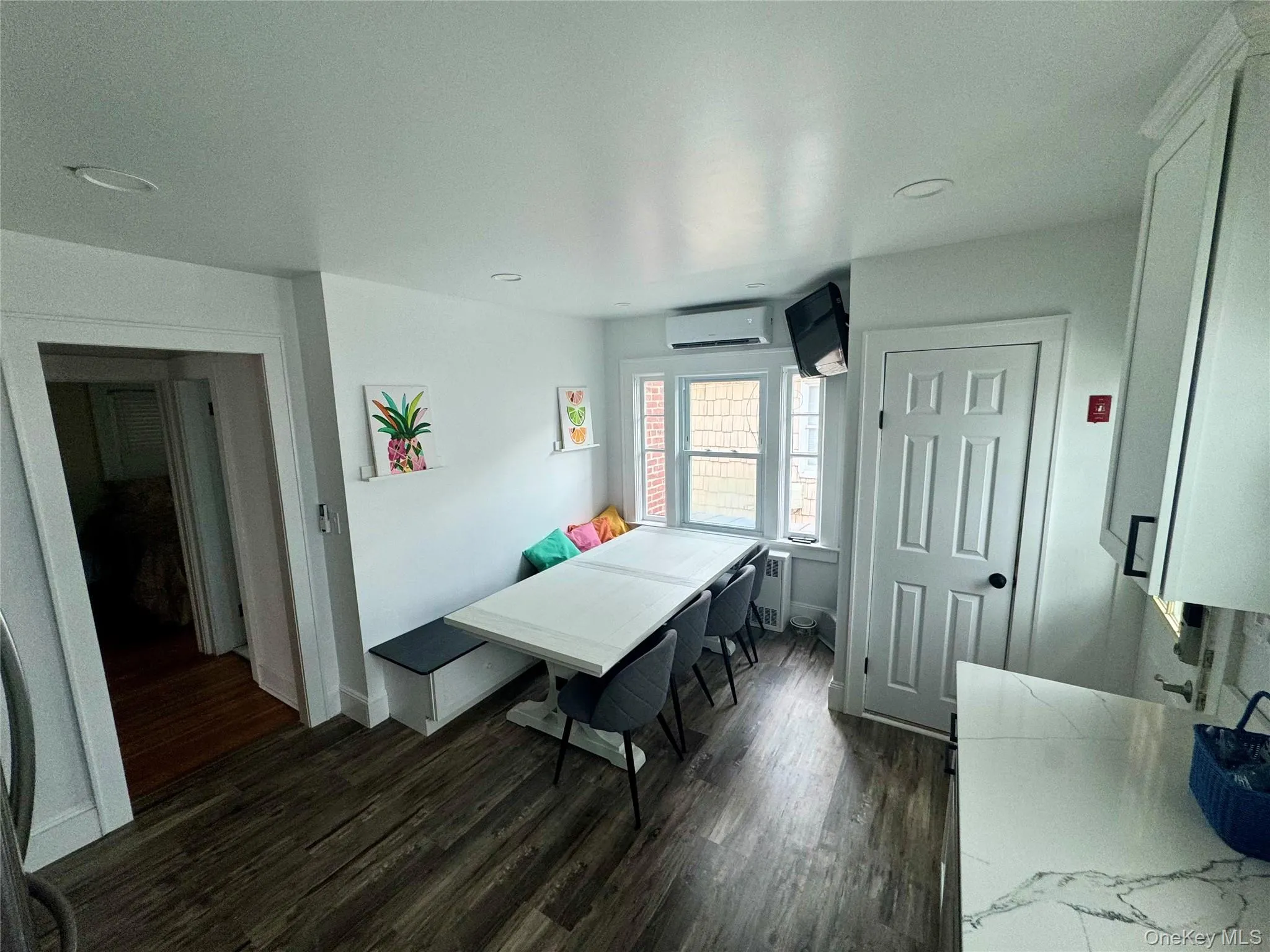 Dining space with dark wood-type flooring, radiator, and a wall mounted AC Dining space with dark wood-type flooring, radiator, and a wall mounted AC
