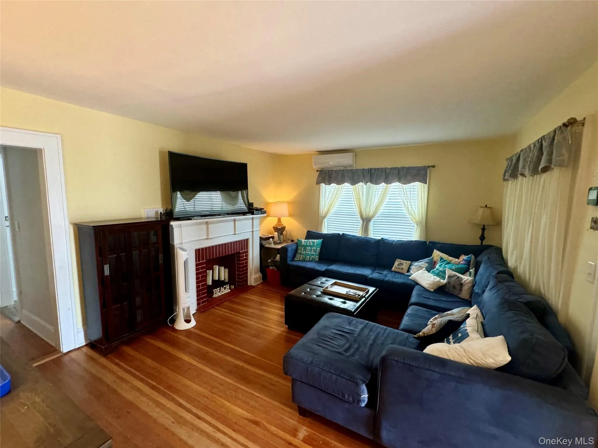Living area with wood finished floors and a brick fireplace Living area with wood finished floors and a brick fireplace