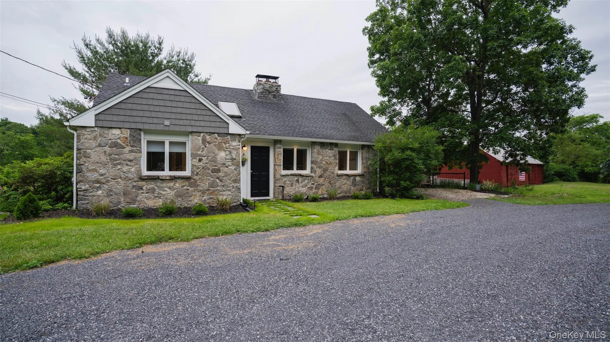 View of front of property with stone siding, roof with shingles, a chimney, and a front lawn View of front of property with stone siding, roof with shingles, a chimney, and a front lawn