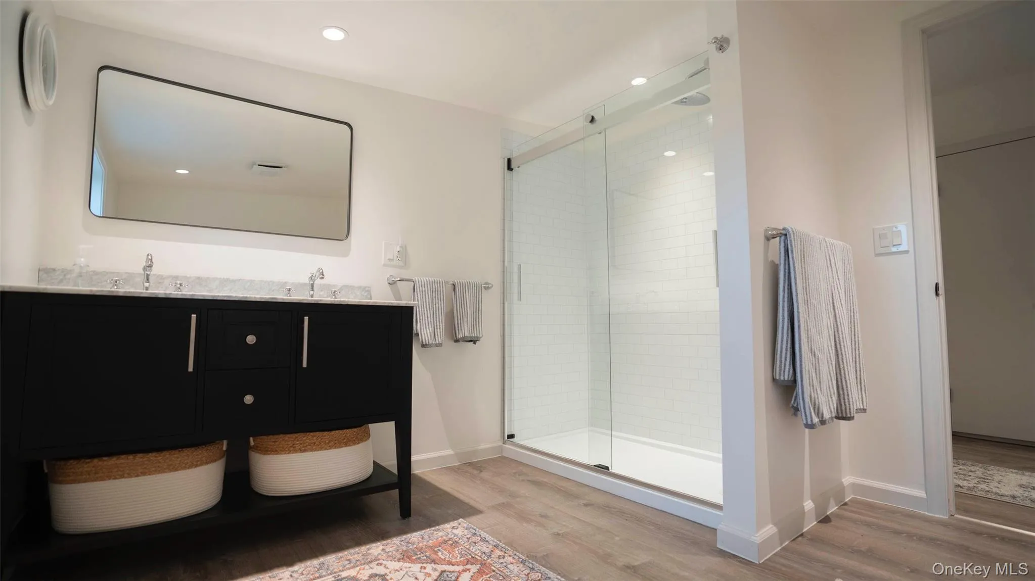 Full bath featuring wood finished floors, double vanity, a stall shower, and recessed lighting Full bath featuring wood finished floors, double vanity, a stall shower, and recessed lighting