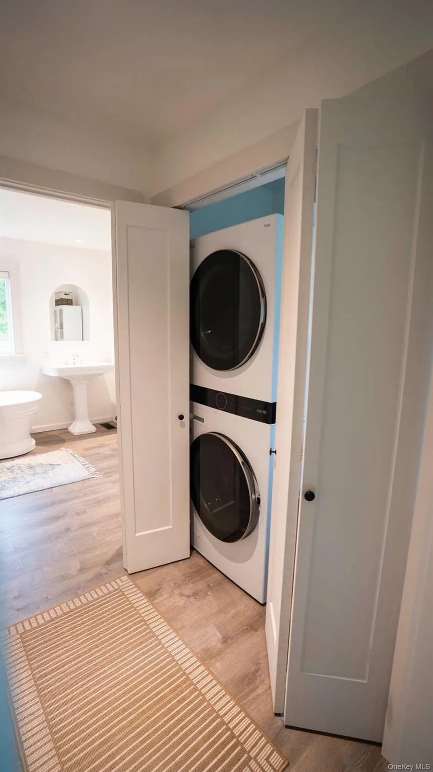 Laundry area with stacked washing machine and dryer and light wood-style floors Laundry area with stacked washing machine and dryer and light wood-style floors