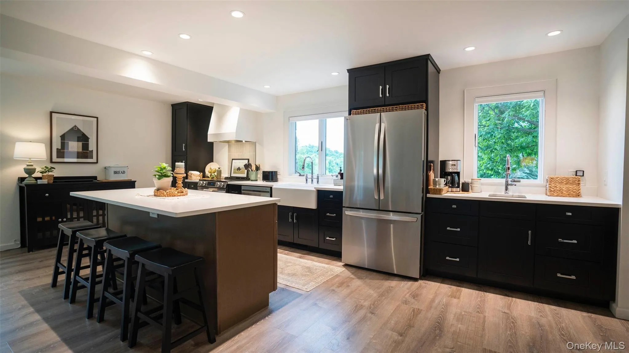 Kitchen featuring freestanding refrigerator, dark cabinets, a breakfast bar area, healthy amount of natural light, and recessed lighting Kitchen featuring freestanding refrigerator, dark cabinets, a breakfast bar area, healthy amount of natural light, and recessed lighting