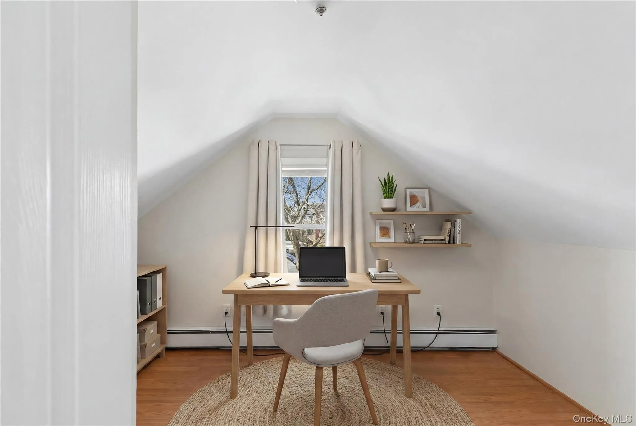 Attic space with sloped ceilings, hardwood flooring, and a single window with drapes Attic space with sloped ceilings, hardwood flooring, and a single window with drapes