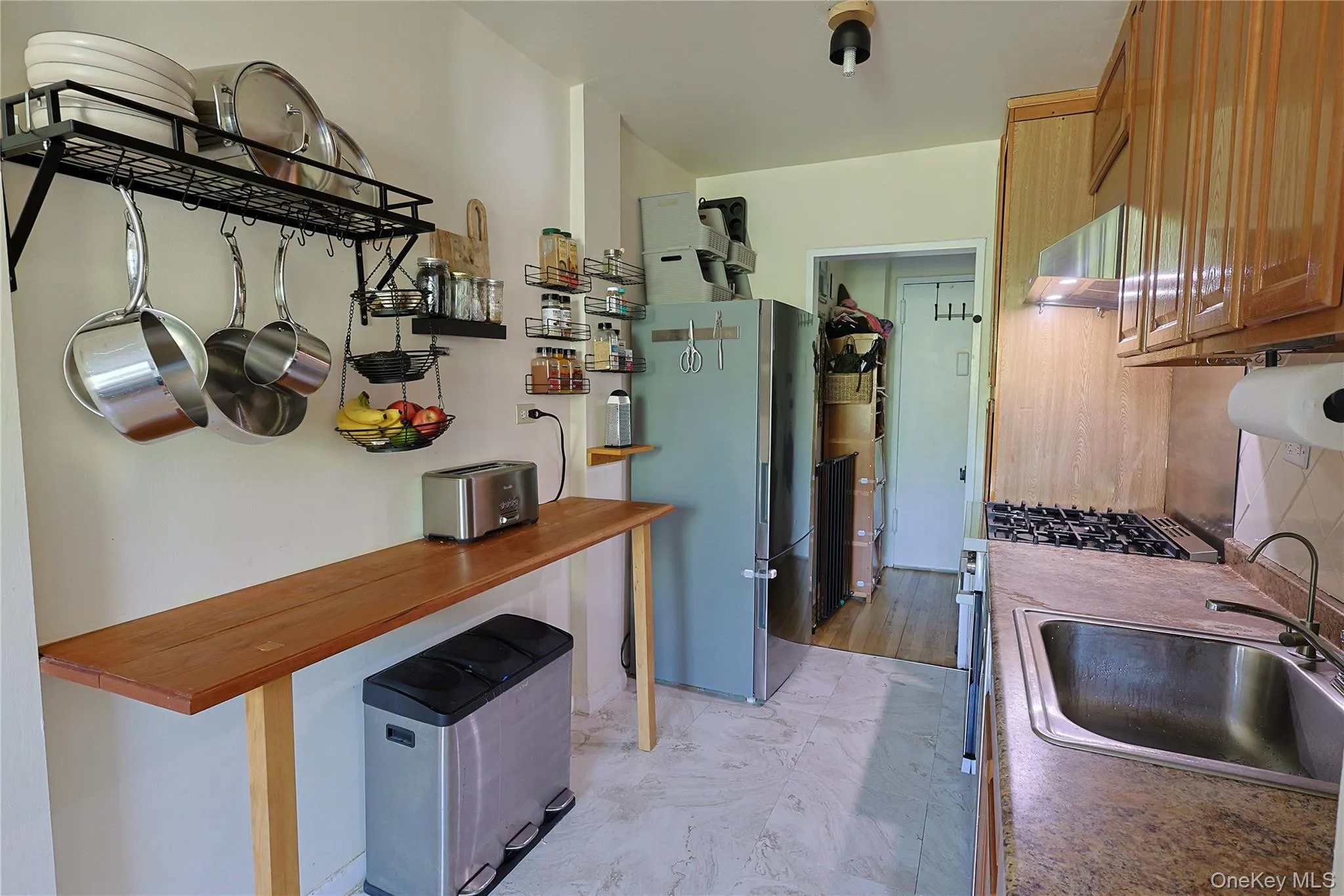 kitchen featuring a gas range, stainless steel sink, wood-finish cabinetry, and a light-toned countertop kitchen featuring a gas range, stainless steel sink, wood-finish cabinetry, and a light-toned countertop