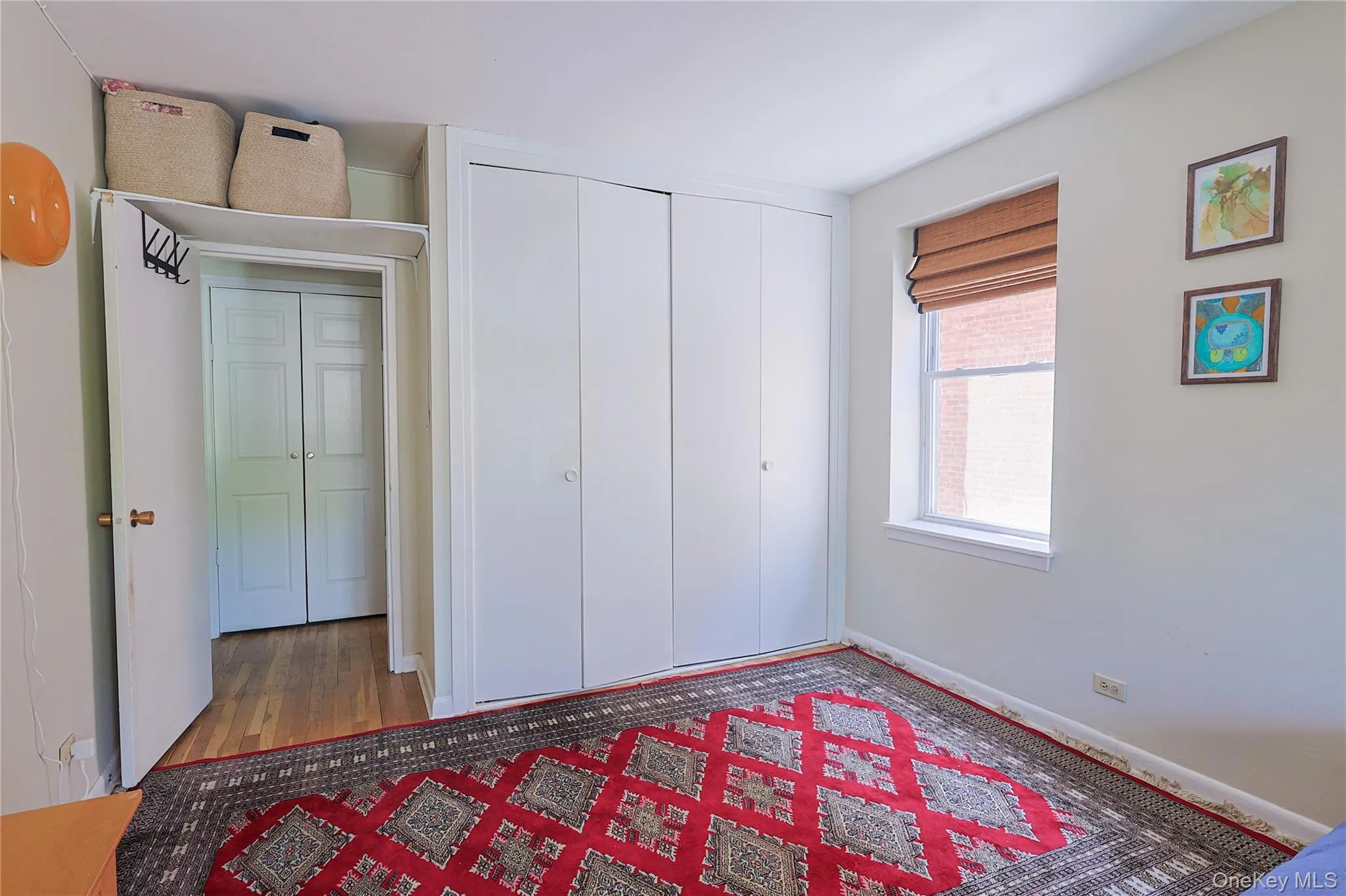 Bedroom featuring light wall paint, wood-finish flooring, and bi-fold closet doors Bedroom featuring light wall paint, wood-finish flooring, and bi-fold closet doors