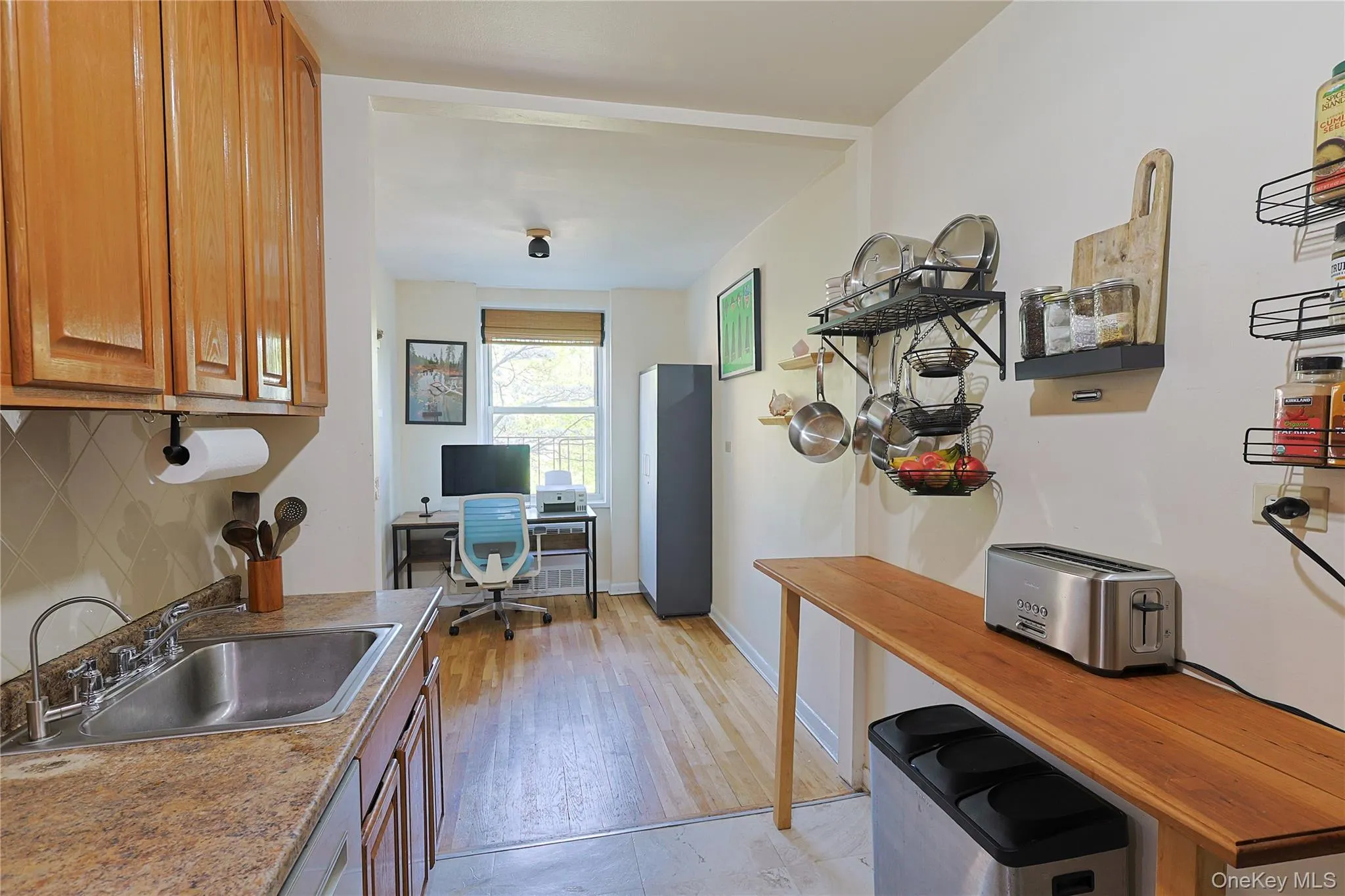 Kitchen featuring wood cabinetry, a stainless steel sink, and stone-look countertops Kitchen featuring wood cabinetry, a stainless steel sink, and stone-look countertops