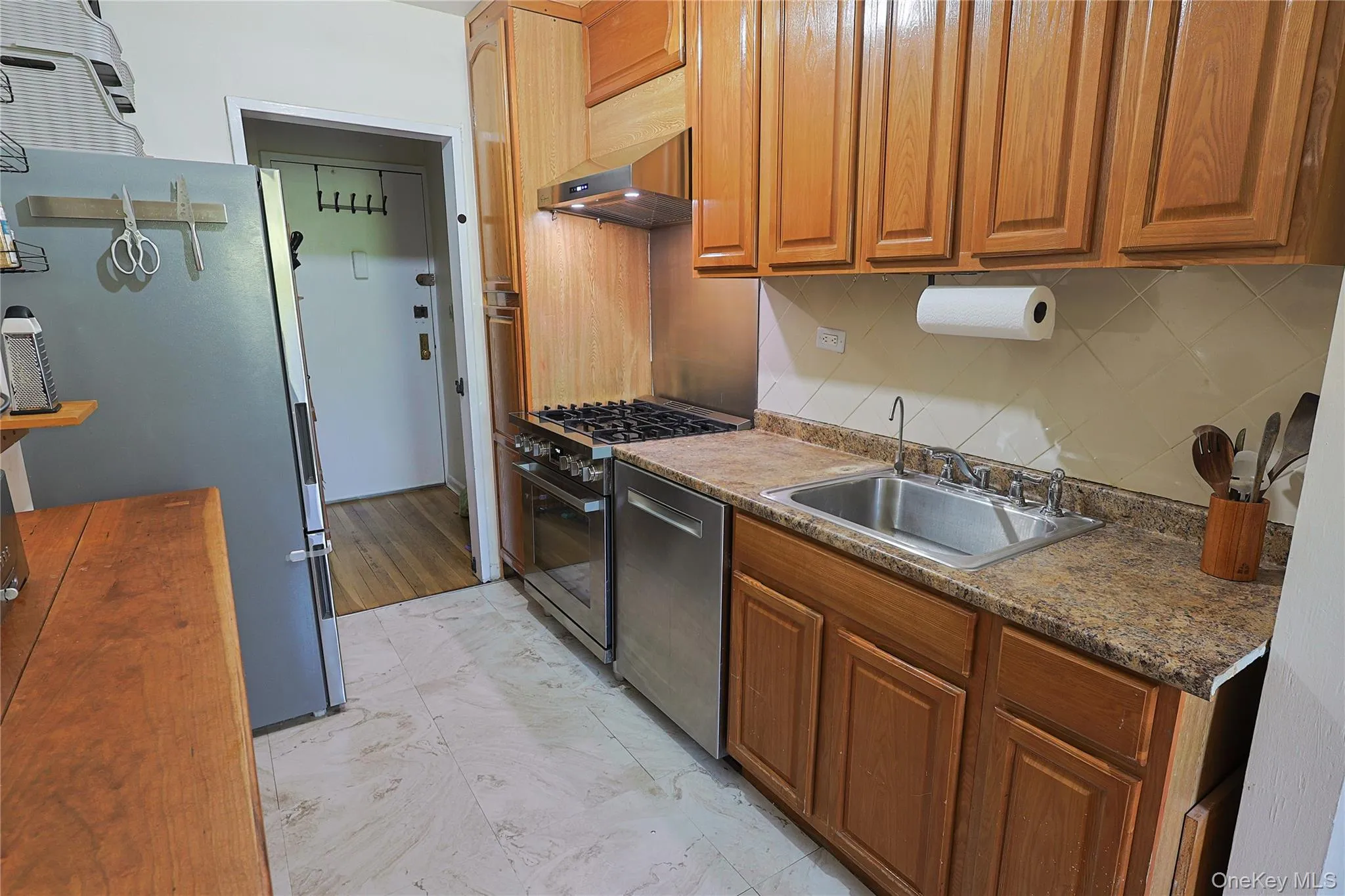 Kitchen featuring wood cabinetry, stainless steel appliances, a double basin sink Kitchen featuring wood cabinetry, stainless steel appliances, a double basin sink