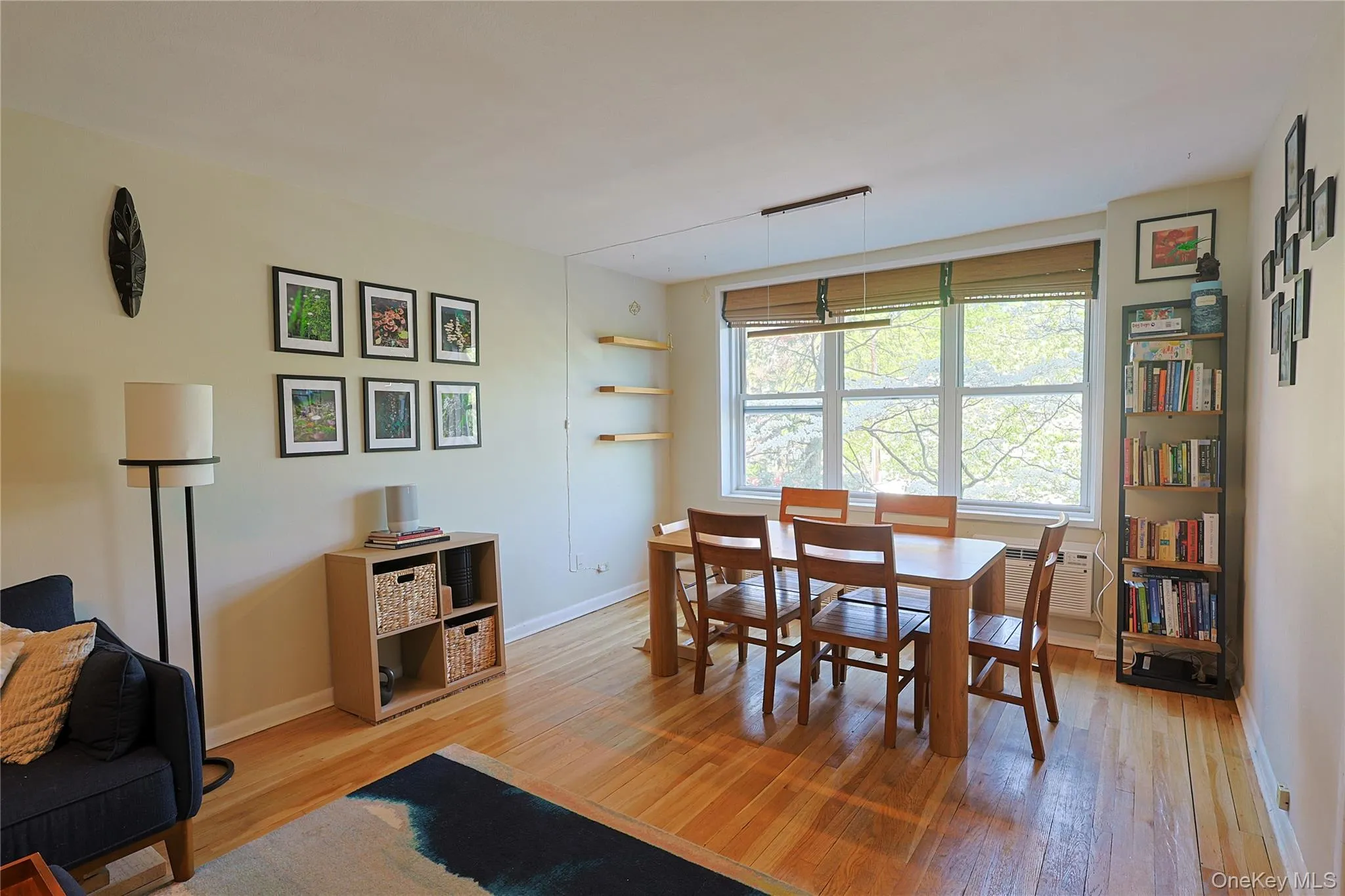 Hardwood flooring throughout a bright living space featuring a large window Hardwood flooring throughout a bright living space featuring a large window