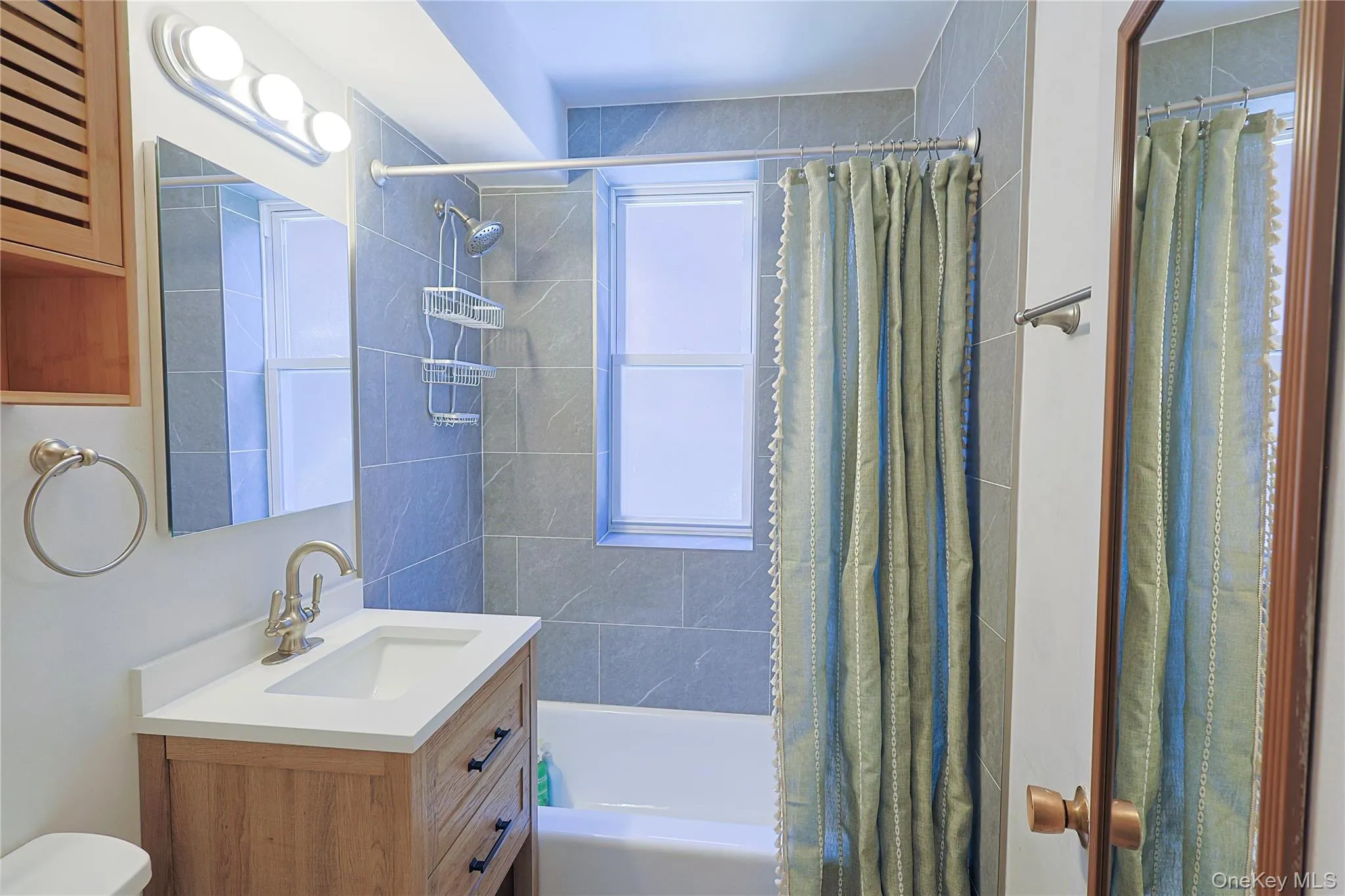 Bathroom featuring a wood-finish vanity with a white countertop and bronze-finish hardware Bathroom featuring a wood-finish vanity with a white countertop and bronze-finish hardware