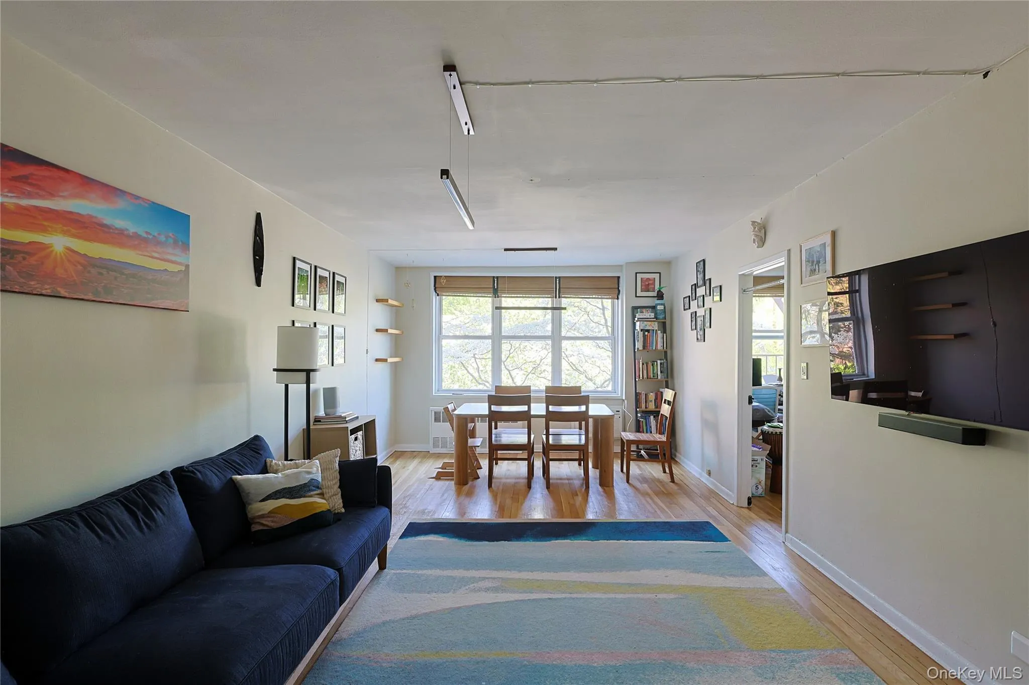 Open-concept living space featuring wood-finish flooring, neutral wall tones, and a window with natural light Open-concept living space featuring wood-finish flooring, neutral wall tones, and a window with natural light