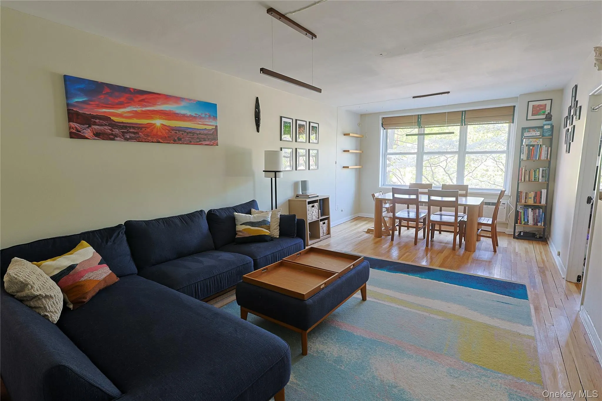 Bright living area with wood-finish flooring, a large window Bright living area with wood-finish flooring, a large window